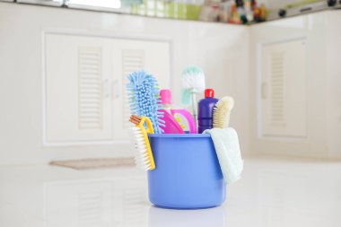 Ev temizliği gerekli. Deterjan, fırça ve malzemelerle dolu plastik bir kova mutfak zemininde oturur ve rutin temizlik işlerini daha kolay ve verimli hale getirir..