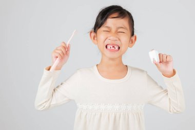Çocuk diş fırçası ve diş mankeni tutuyor, diş hekimi diş kaybını açıklıyor. Asyalı çocuk gülüşü, kayıp süt dişleri ve boşluk, diş temizliği alışkanlıkları. izole edilmiş beyaz arkaplan