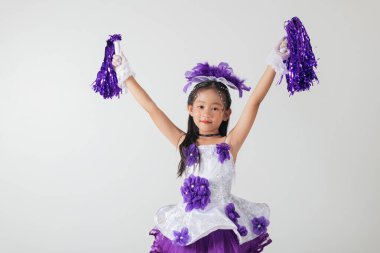 Mor ve beyaz üniformalı gülümseyen ponpon kız. Stüdyo fotoğrafı, temiz beyaz bir arkaplan. Gençlik enerjisi ve kutlama. Amigo kız.