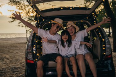 Asyalı bir aile gün batımında arabalarıyla sahilde oturuyor. Tatillerde ve tatillerde kendilerini tuhaf hissediyorlar. Baba, anne-kız iyi hafta sonları tatilleri. Plajda iyi eğlenceler. Yaz tatili kamp gezisi