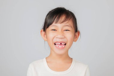 Mutlu Asyalı kız için dişçiden diş dökülmesi dersi, kayıp dişle gülümsüyor. Çocuk boşluklar gösteriyor, diş bakımını öğreniyor ve kaybettikten sonra sağlıklı dişler çıkarıyor. izole edilmiş beyaz arkaplan