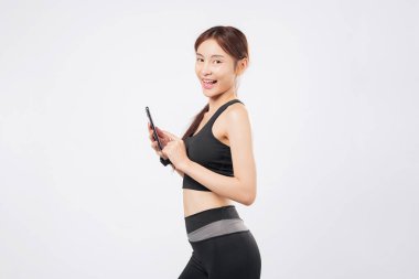 Elde telefon ve başka bir telefondan sonra bu formda sporcu kadın spor kıyafetlerini giyerek spor salonuna olan bağlılığını ve mobil yaşam tarzını sergiliyor. izole stüdyo beyaz arkaplan
