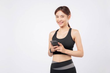 Başka bir telefon hareketini kullanırken telefonu tutan bu sportif kadın, spor yaşam tarzını ve teknolojik alışkanlıklarını özgüvenli bir spor salonu portresi ile dengeliyor. izole stüdyo beyaz arkaplan