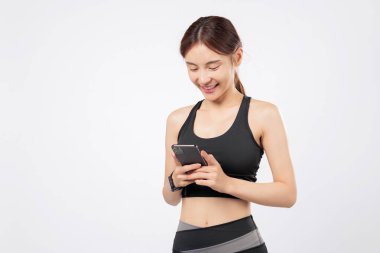 Telefon tomarı ve günlük telefon kullanımı spor ayakkabıları rutinini ön plana çıkarıyor, spor elbiseli mutlu bir kadının spor ve sosyal zamanını zahmetsizce yönettiğini gösteriyor. izole stüdyo beyaz arkaplan