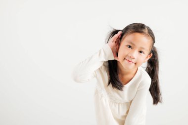 Asyalı genç bir çocuğun portresi, kulak misafiri olurken gülümsemesi kulak misafiri oluyor. Kulak üstüne kulak çekimleri, beyaz arka planda izole edilmiş fotokopi odası işitme hareketi, anaokulu kızı.