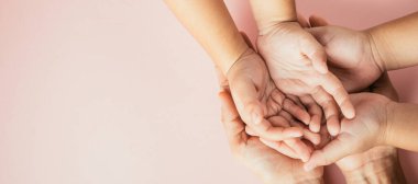 Ebeveynler ve çocuklar el ele tutuşuyorlar. Renkli arka planda soyutlanmışlar. Aile Günü birliktelik ve desteği kutluyor..