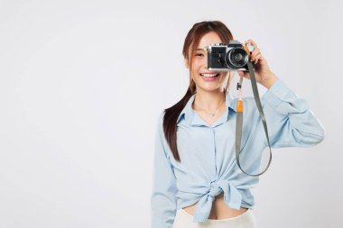 Gezgin, fotoğraf makinesiyle fotoğraf çekiyor. Mutlu gülümseyen Asyalı genç kadın yaz tatilinde fotoğraf macerasının tadını çıkarıyor. izole stüdyo beyaz arkaplan