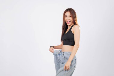 İnce ve kendinden emin bir şekilde, kocaman pantolonları içinde duruyor ve gülümsüyor. İnce şekli, disiplin ve kendine bakmanın hikayesini anlatıyor. izole stüdyo beyaz arkaplan