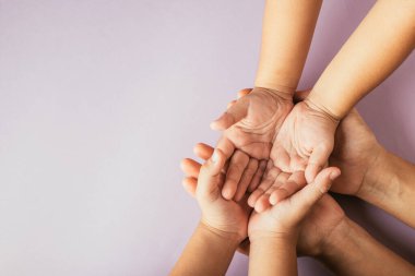 Ebeveynler ve çocuklar boş elleriyle üst tarafa bakıyorlar. Renkli arka planda izole olmuşlar. Aile Günü birliği desteği ve nesiller arasındaki bağın göstergesi.