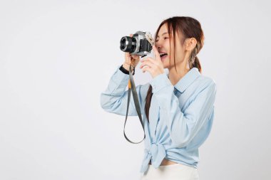 Kamera olay yerini gösteriyor, gezgin turist fotoğraf makinesiyle çekim yapıyor. Heyecanlı Asyalı genç bayan seyahat fotoğrafçılığının tadını çıkarıyor. izole stüdyo beyaz arkaplan