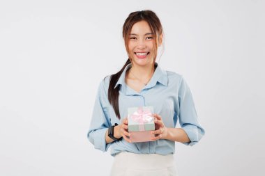 Sevinçten gülümseyen genç bir kadın tarafından tutulan pembe kurdeleli hediye. Kalbine yakın hediye kutusunu tutarken özel anını kutluyor. Portre izole edilmiş stüdyo beyaz arka plan