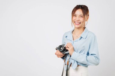 Elinde fotoğraf makinesi olan turist gülümsüyor. Klasik turist seyahatinin tadını çıkarıyor. Seyahat eden Asyalı genç kadın huzurlu bir tatil sırasında mutlu anları yakalıyor. izole stüdyo beyaz arkaplan