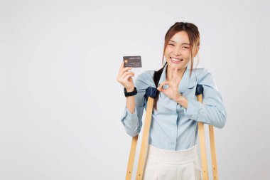 Koltuk değnekleri yaralı kadının ayak kırığı gösterisine yardımcı olur. İkinci koltuk değnekleri yakında duruyor. Bu da sigorta onayı ve kazadan sonraki mali başarıyı gösteriyor. izole edilmiş beyaz arkaplan