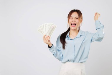 Asyalı kadın elinde para tutarak gülümsüyor, heyecanla yumruğunu kaldırıyor, şanslı anı ve fazladan parayı kutluyor. Para birimi yükseltildi yumruk izole stüdyo beyaz arka plan
