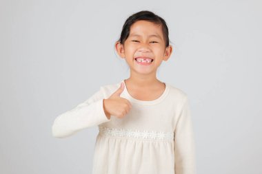 Mutlu bir çocuk diş boşluğu göstererek baş parmağını kaldırır. Diş hekimi diş kaybını ve sağlıklı büyüme için yeni diş boşluğuna nasıl bakılacağını açıklıyor. beyaz arkaplanda izole