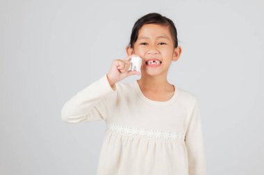 Mutlu kız elinde diş modeliyle dişlerini göstermiş. Boşluklu sevimli gülümseme, çocuk gelişimi konsepti, diş bakımı ve çocuklarda diş kaybı. izole edilmiş beyaz arkaplan