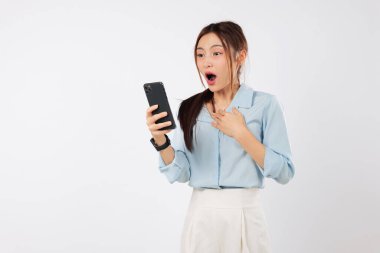 Cep telefonunu tutan genç Asyalı kadın şokta, gerçekten şaşırmış görünüyor. Haberlerde, akıllı telefonunun şokuyla hayret içinde olduğunu söylüyor. izole stüdyo beyaz arkaplan