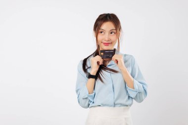 Elinde kredi kartı tutan gülümseyen Asyalı genç bir kadın, onu para ve ödeme için sunuyor, çevrimiçi iş için banka kartını gösteriyor, mal ve hizmetler için kart ödemesi yapıyor, izole edilmiş beyaz bir geçmişi var.