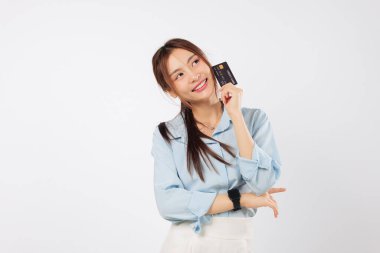 Gülümseyen genç Asyalı kadın kredi kartı tutuyor, ne alacağını düşünüyor, fotokopi alanına bakıyor, belki özel bir hediye, para bankası kartı hazır, izole edilmiş stüdyo beyaz arka plan