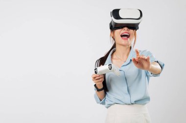 Neşeli bir Asyalı kadın olarak VR oyunu sopa kontrolörüyle oynar, dijital sanal panel alanına dokunurken ya da işaret ederken gülümserek. izole stüdyo beyaz arkaplan