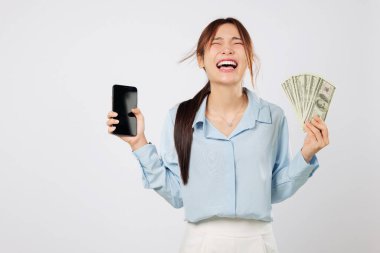 Cep telefonu ekranı ve para gösteren mutlu Asyalı kadın, internet uygulaması para başarısı, dijital iş büyümesini kutlayan kendine güvenen bir gülümseme ve dolar hayranı. izole edilmiş beyaz arkaplan