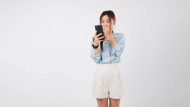 Kadın şok edici Asyalı. Şaşırtıcı bir ağzı var. Duygu yüklü cep telefonu okuyor, cep telefonunda kötü haberler görüyor.