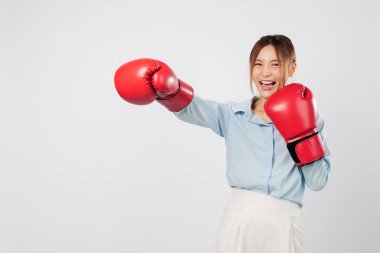 Boks enerjisi ve boks yumruğu kırmızı eldivenli Asyalı genç iş kadını tarafından gösterildi. Güçlü gülümseme ve boksör duruşu onun gücünü ve kickboks ruhunu ortaya çıkarıyor. izole stüdyo beyaz arkaplan