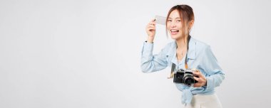 Mutlu Asyalı kadın seyahat malzemeleri alırken yakalanan seyahat anı. Elinde antika bir fotoğraf makinesi ve kart bankası tutarak ilerideki yolculuğa gülümsüyor. Turizm ve tatil izole stüdyo beyaz arka plan