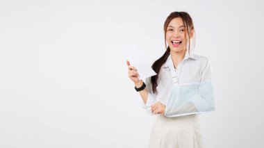 Kazadan sonra faturaları ödeyen mutlu Asyalı kadın sigortası, kol kırığı desteğini gösteriyor, kazadan sonra hayat ve sağlık sigortası için minnettar, stüdyo beyaz arka planı izole edilmiş.