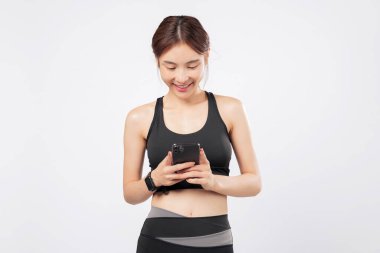 Siyah spor kıyafetli, formda bir kadından gelen bir telefon dinlemesi fitness uygulamalarına, spor rutinlerine ve spor hayatına bağlı kalmaya olan sevgisini gösteriyor. izole stüdyo beyaz arkaplan