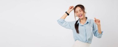 Kulaklıkla müzik dinlerken gülümseyen Asyalı genç kadın, müzik yaşam tarzına ve insan duygularına ritim katarken sevinçle el kaldırıyor. izole stüdyo beyaz arkaplan