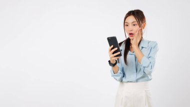 Şok olmuş Asyalı kadın üzgün endişeli görünüyor. Telefonu kullanarak, endişe verici bir mesaj alarak, duyguları şaşırtıyor. Güzel bir Asyalı kadın telefonunu kullanırken şaşırır, izole edilmiş stüdyo beyaz arka plan