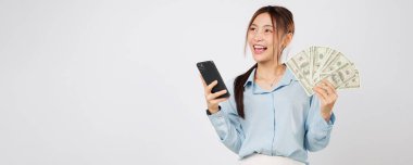 Elinde telefon ve para tutan gülümseyen Asyalı kadın, çevrimiçi alışveriş kazananı heyecanı, dijital anlaşmalardaki para kazancı ve cep telefonuyla yapılan güvenli işlemler sayesinde mutlu. izole edilmiş beyaz arkaplan