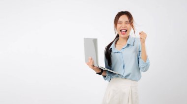 Mutlu Asyalı genç bir kadının dizüstü bilgisayarını tutarak sevinçten havalara uçan ellerini kaldırıyor. Çevrimiçi zaferinin heyecanını hissederken ikinci laptop taşınabilir bilgisayarı da yakınlarda duruyor. izole stüdyo beyaz arkaplan