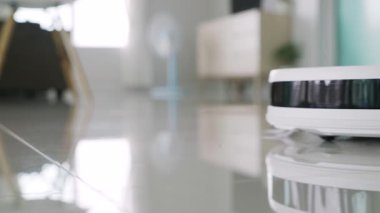 Ön siyah sensör şeritli, fayans zemininde yan fırçası olan beyaz otomatik yer temizleyicisi. Robot elektrikli süpürge zemini etkin bir şekilde temizliyor, toz temizleme için akıllı ev teknolojisini gösteriyor