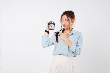 Acelesi olan Asyalı kadın saati hedef ve zaman yönetiminin hatırlatıcısı olarak tutuyor. Mesajını vurgulamak için saati gösteriyor. Stüdyonun beyaz arka planında çekilmiş vesikalık fotoğrafı.