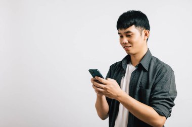 Mutlu bir gencin portresi, Asyalı bir gencin akıllı cep telefonuna online iletişim için bir mesaj yazması. Stüdyo görüntüsü beyaz üzerine izole edilmiş, teknoloji meraklısı doğasını vurguluyor..
