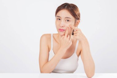 Alnının etrafında sivilceler belirirken burnunun yanındaki sivilceler endişeye neden oluyor. Beneklerini sıkıyor ve cilt bakımını dürüstlük ve öz farkındalıkla ele alıyor. izole stüdyo beyaz arkaplan