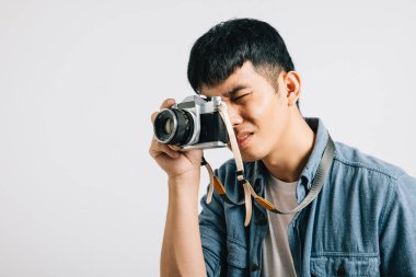 Mutlu bir gencin portresi, antika bir kamerayla yakın çekimine hazır. Stüdyo çekimi beyaz arkaplanda izole edildi. Bu ekran görüntüsü ihtişam ve filmden esinlenilmiş stil yayar..