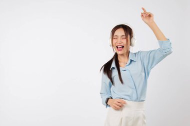 Müzik enerji getirirken, genç Asyalı bir kadın ellerini kaldırarak dans ediyor ve müzik onun yaşam tarzına ve duygusal hislerine mutluluk katıyor. izole stüdyo beyaz arkaplan