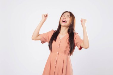 Başarı başarıyla dolup taşarken bu kadın gülümsüyor ve heyecan içinde yumruklarını kaldırıyor güven motivasyonu ve izole edilmiş stüdyo beyaz arka planını kazanan bir iş.