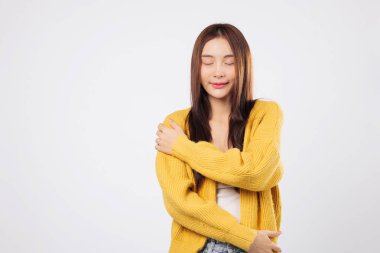 Ruhun kucaklaması, anın kucaklaması. Kendine güvenen Asyalı kadın, kolları omuzlarının üzerinde, gözleri kaygısız ve sakin bir şekilde kapalı barışçıl bir hareket sergiliyor. izole edilmiş beyaz arkaplan