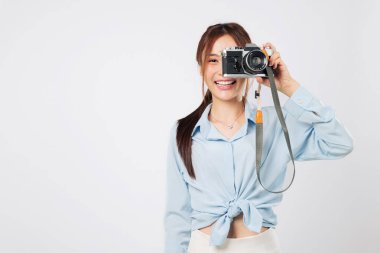 Kamera sıkıca sarılmış, neşeli gülümsemeli turist fotoğraf makinesiyle fotoğraf çekiyor. Mutlu Asyalı genç kadın tatilde güneşli bir seyahat sırasında anılarını yakalıyor. izole edilmiş beyaz arkaplan