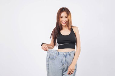 İnce bel, genç bir kadının, büyük beden pantolonunu gururla gösterdiğini gösteriyor. İnce yapısı, sağlıklı seçimlere aylarca adanmışlığı yansıtıyor. izole stüdyo beyaz arkaplan