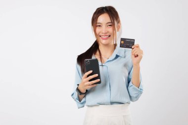 Mutlu Asyalı kadın cep telefonu kullanarak kredi kartıyla ödeme yapıyor. İnternetten alışveriş ve finans kartı tutuyor. izole stüdyo beyaz arkaplan