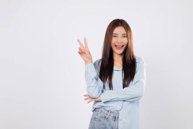 Zafer parmakları neşeli bir ifadeyle kaldırıldı, gülümseyen Asyalı bir kadınla zafer anını kutluyorlar. Barışçıl bir jest, beyaz arka planda izole edilmiş neşeli bir V işaretinde iki parmak yukarı..