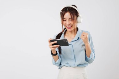 Oyun, Asyalı kadının elinde telefonla kulaklık takmasıyla başlar. Oynamak için heyecanlanır ve neşe ve enerjiyle el kaldırarak zaferi kutlar. izole stüdyo beyaz arkaplan