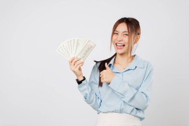 Gülümseyen Asyalı kadın heyecanlı hissediyor, parayı gösterirken başparmağından vazgeçiyor, para hayranı bir kazanan gibi gururlu, başarı ve kişisel başarı izole edilmiş beyaz bir arka plan