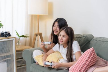 İki genç arkadaş evde video oyunu oynuyor, gençler konsol oyun kontrolörleri oynamaktan hoşlanıyor, günlük ev aktiviteleri arkadaşlara eğlence ve eğlence sağlıyor, birlikte gülüp kaynaşıyorlar..