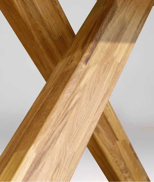 Wooden table legs isolated over gray background, close view photo, crossed star shaped legs, wooden eco furniture elements background. Solid wood furniture details